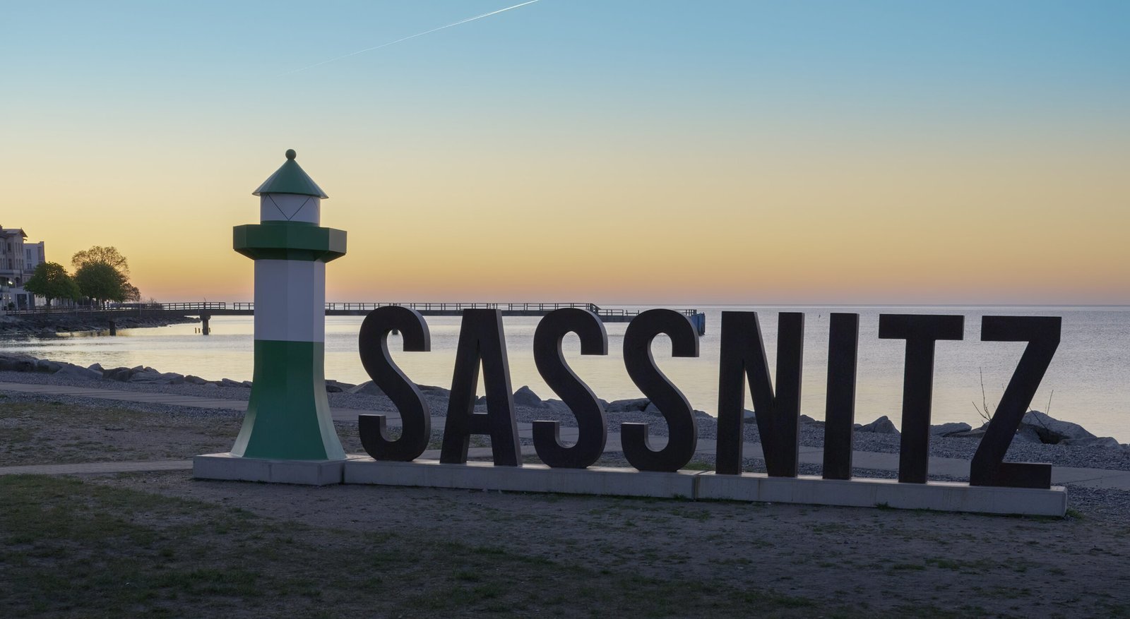 Titelbild Album Sassnitz, Foto vom Strand mit dem Schriftzug Sassnitz und einem Deko-Leuchtturm.