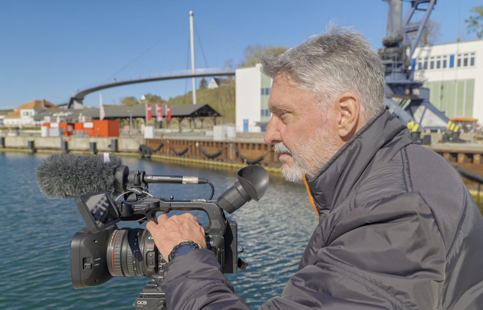 Kameramann Werner Wilmes in Aktion hinter seiner Kamera, Hintergrund Hafen Sassnitz, Rügen