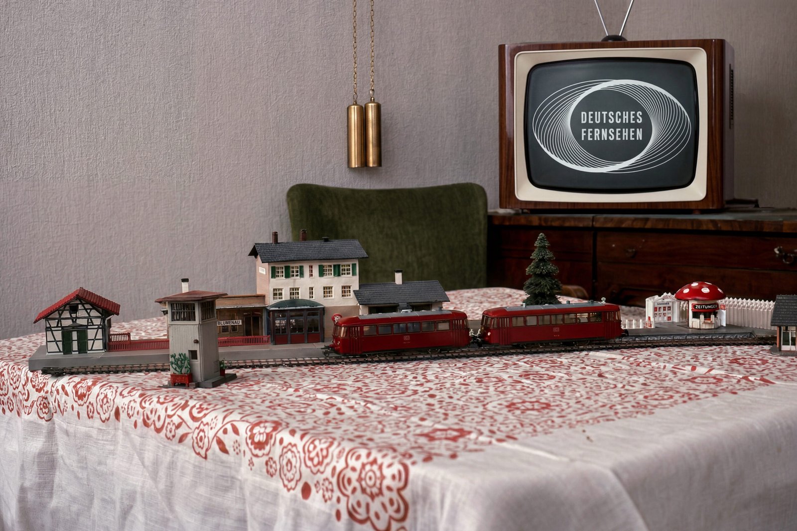 Deutsches Fernsehgerät von 1962 und ein Teil einer Modellbahnanlage auf dem Tisch davor mit einem roten Schienenbus
