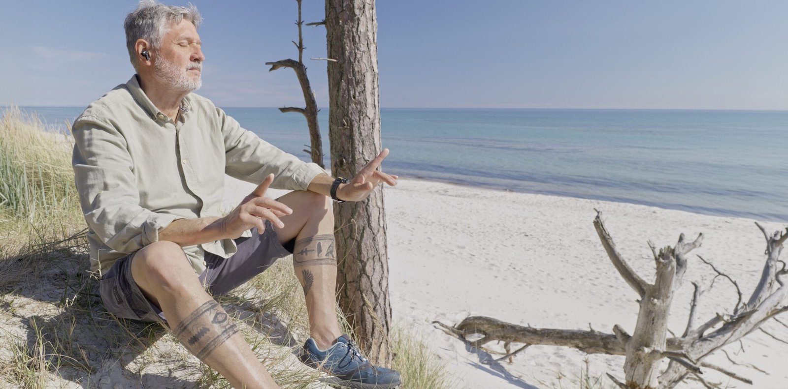 Mann am Strand mit Kopfhörern im Ohr hört mit geschlossenen Augen Musik. Der Mann ist Werner Wilmes